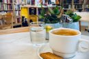 Eine Tasse Kaffee im Vordergrund, die Buchhandlung im Hintergrund