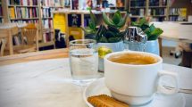 Eine Tasse Kaffee im Vordergrund, die Buchhandlung im Hintergrund