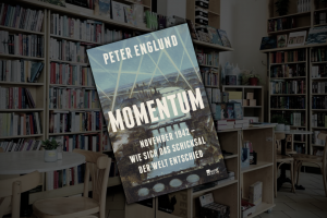 Zu sehen ist ein Buch mit der Aufschrift "Momentum". Im Hintergrund die abgedunkelte Buchhandlung.